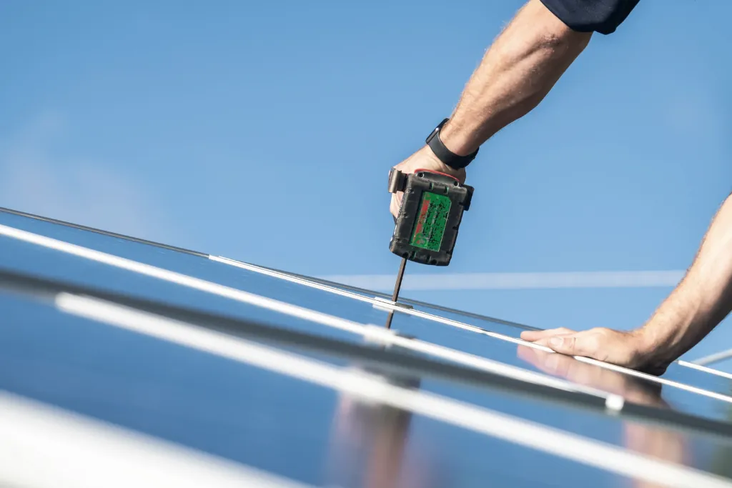 Instalador fijando placas solares en un tejado.